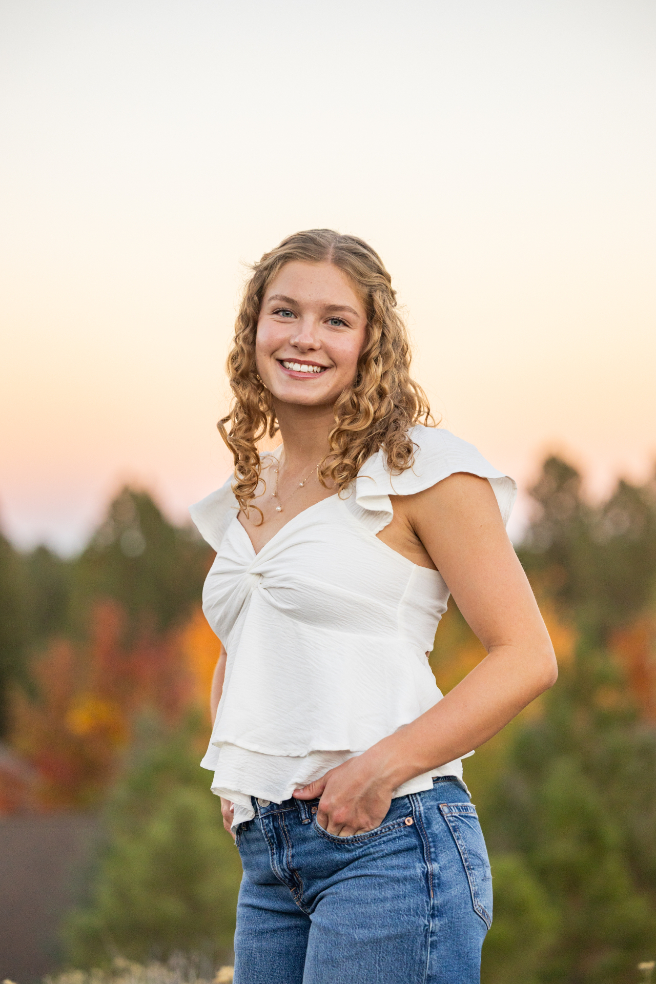 Smiling senior girl in a white top with soft evening light behind her