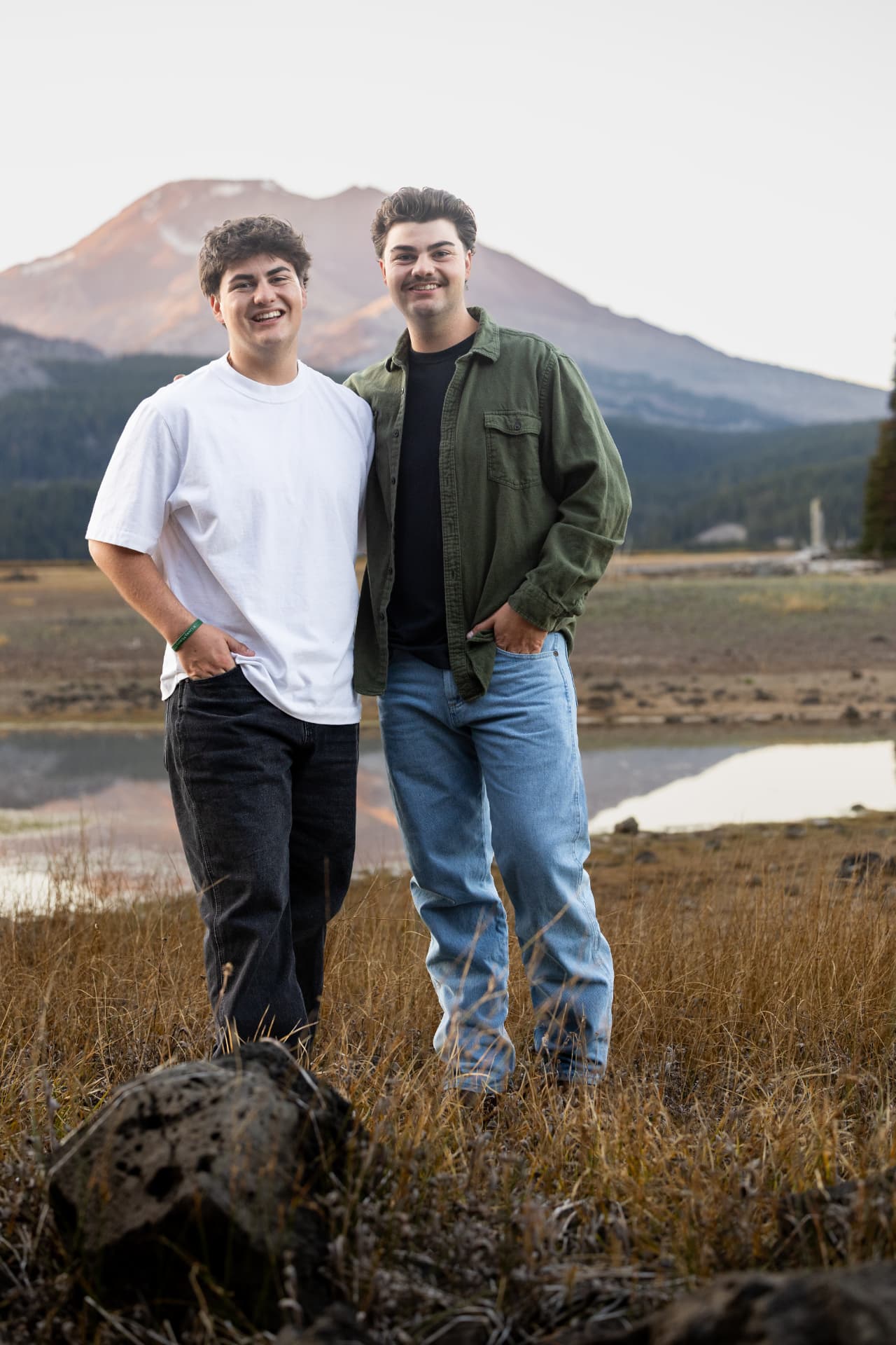 Two brothers standing together beside a mountain lake