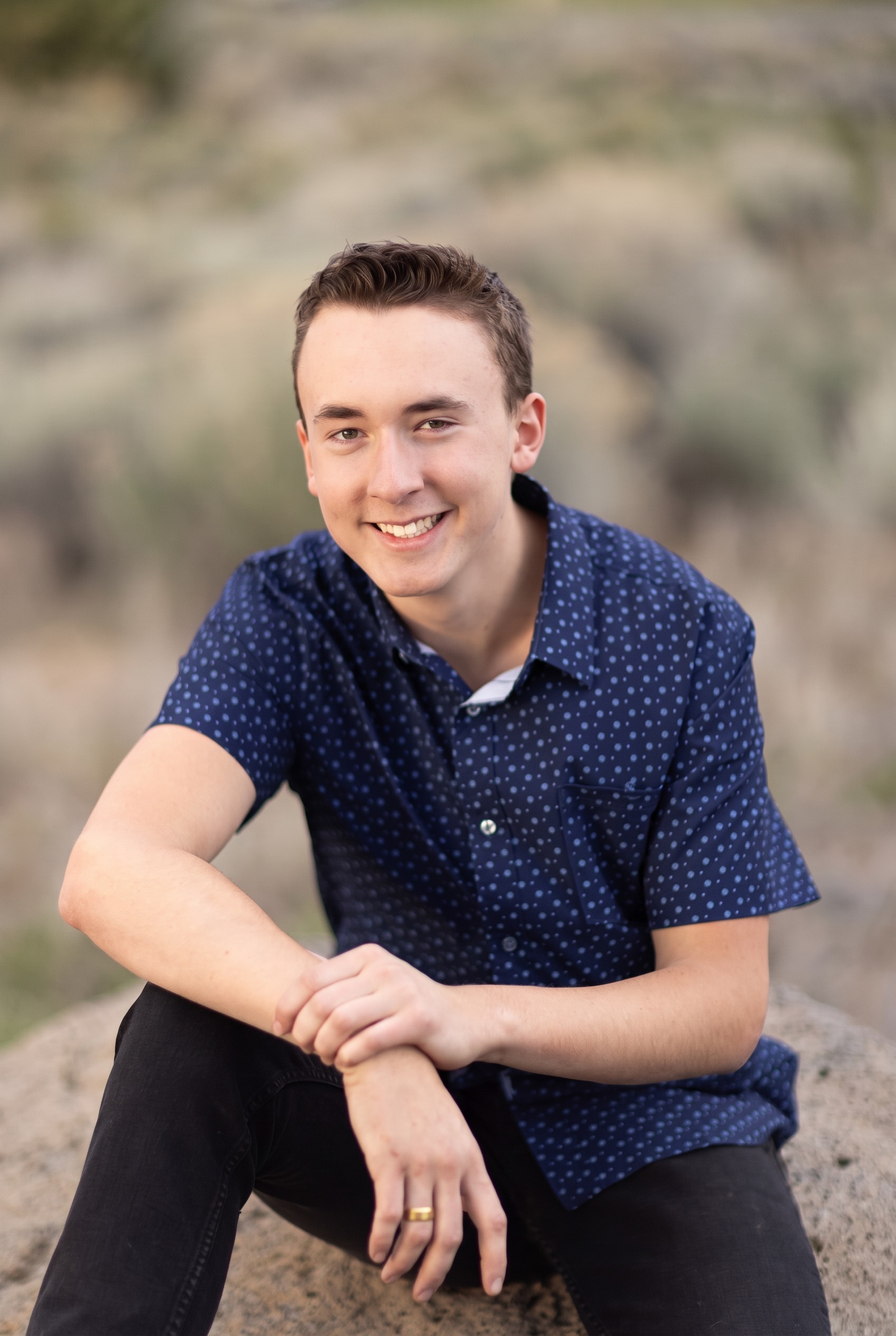 Senior guy smiling while seated on warm rocks in the high desert